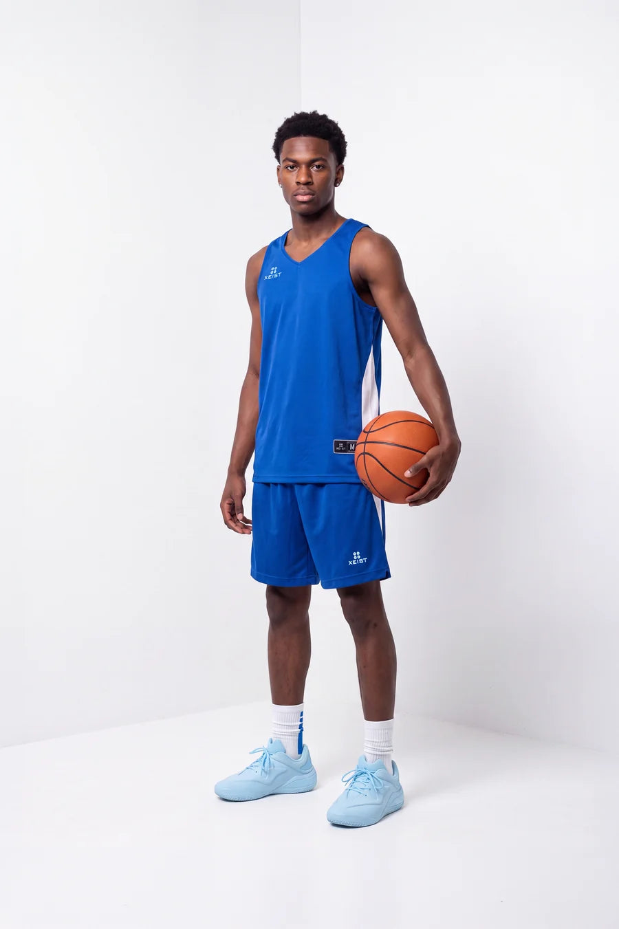 Player in the blue XEIST basketball uniform holding a ball